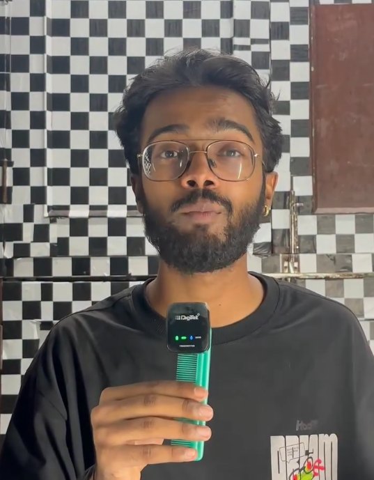 Pranjul Rathour in a black t-shirt holding a microphone in front of a chequered wall