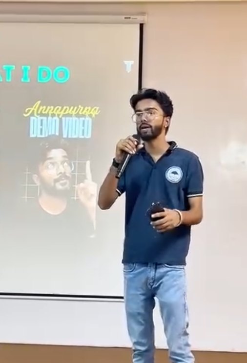 Pranjul Rathour presenting on stage in a blue polo, with his Annapurna demo video on the screen behind him